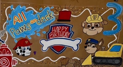 Birthday banner with three puppies in work hats, a red shield, white bone, yellow bulldozer, fire hydrant, and blue number three