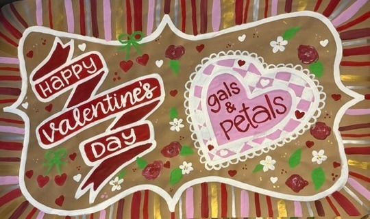 Hand-painted Valentine's Day banner on kraft paper with script lettering on a flowing red ribbon, roses and hearts, a mosaic-style heart centerpiece, and a pink and red striped border